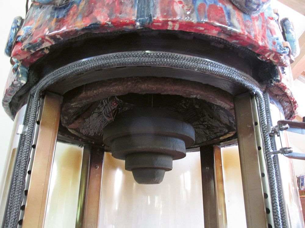 Zavesený kužeľový deflektor z vermikulitu odráža teplo z ohniska von. Možno ním nastaviť veľkosť otvoru na odtok spalín.