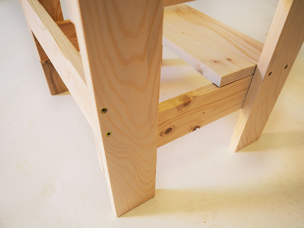 Zadná vzpera. Bočné steny stolčeka zafixujte pomocou spodnej vzpery, ktorú upevníte z opačnej strany spodných bočných podpier, ako sú nášľapné dosky. Aj vzperu upevnite pomocou štyroch skrutiek do dreva z vonkajšej strany stolčeka.