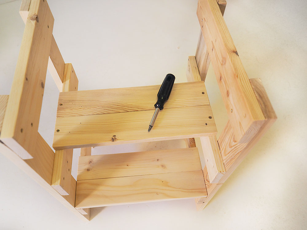 Druhý schodík. Druhé spojené nášľapné dosky umiestnite na stredové bočné podpery vo vzdialenosti 120 mm od predného okraja stolčeka. Do podpier ich upevnite tentoraz zvrchu pomocou skrutiek do dreva (4 × 40 mm).