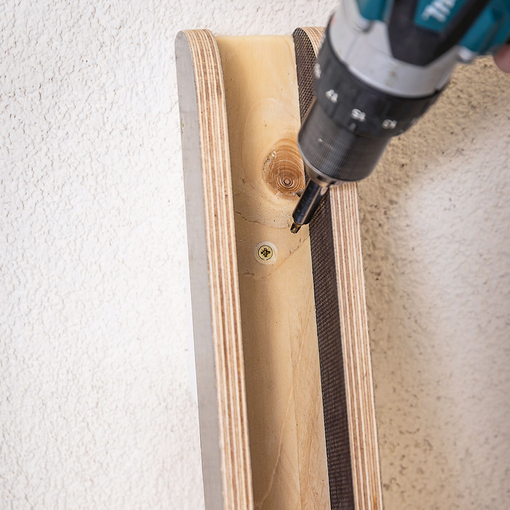 Upevnenie žľabu do steny. Konštrukciu napasujte k stene tak, aby spodný žľab ležal celou plochou na podlahe. Potom upevnite šikmý žľab o klin na stene. 