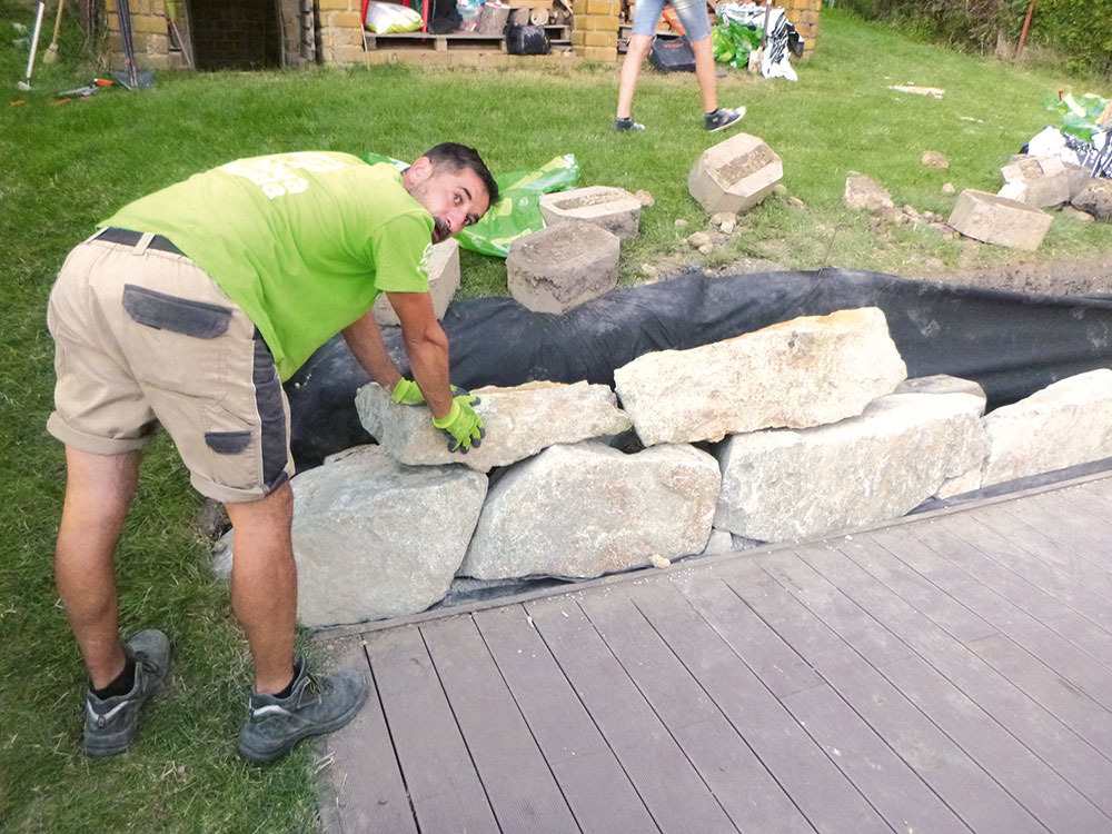 Ukladanie. V ďalších radoch použite menšie kamene. Pri ukladaní postupujte podobne ako pri murovaní tehál. Postupne poskladajte stenu po celej dĺžke, smerom hore sa veľkosť kameňa zmenšuje. 