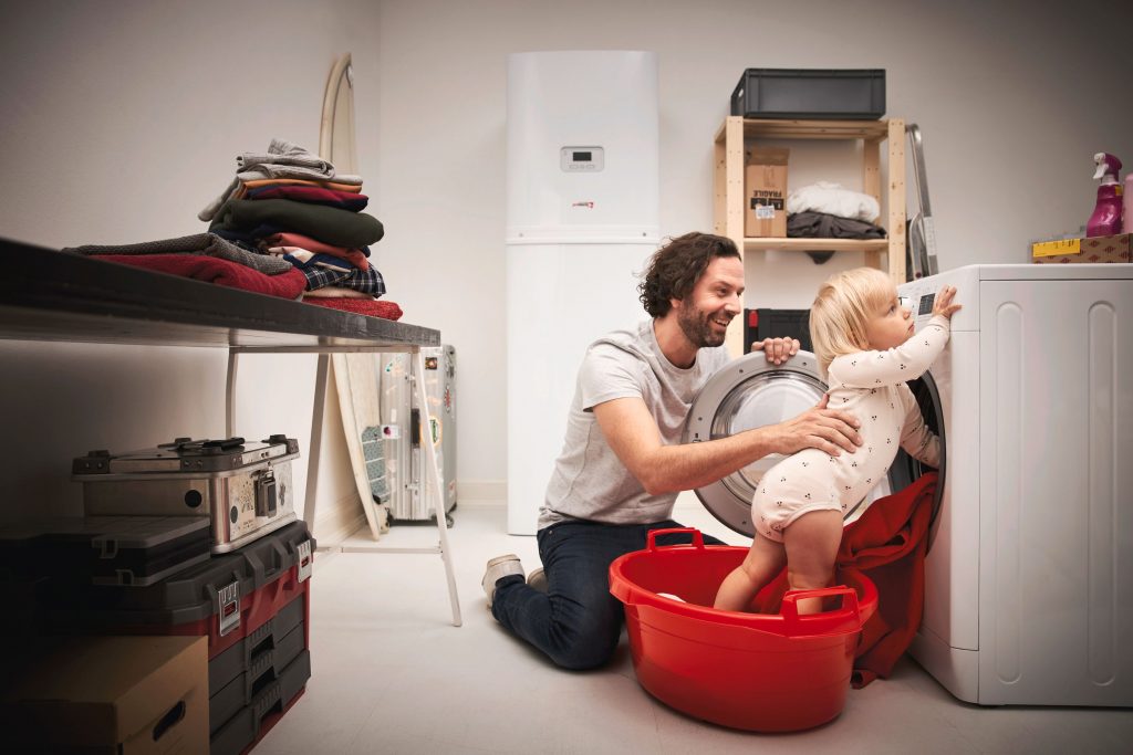 Otec s dieťaťom v technickej miestnosti pri práčke