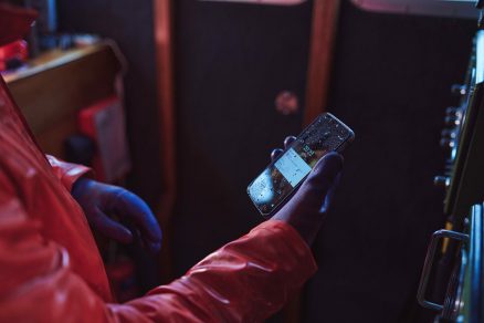 Robotník v rukaviciach drži odolný smartfón