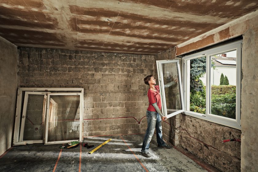 Muž vyberá okno z rekonštrukcie domu