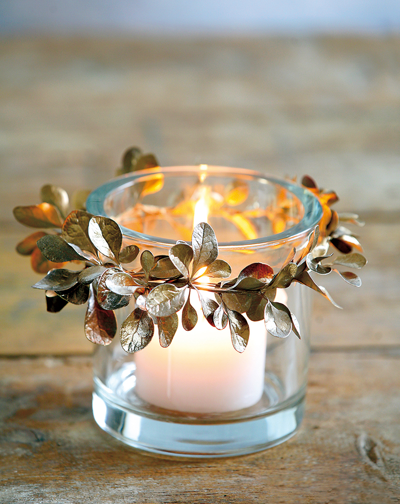 Malý jesenný venček z lístia pripevnený na sklenenom pohári so sviečkou