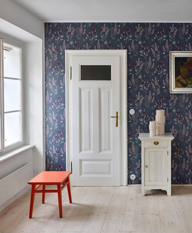Na stene je opäť farebná a výrazná tapeta Ema Dark Greyod Sangberg Wallpaper, ktorá vytvára správny kontrast s bielymi kachľami a nábytkom.