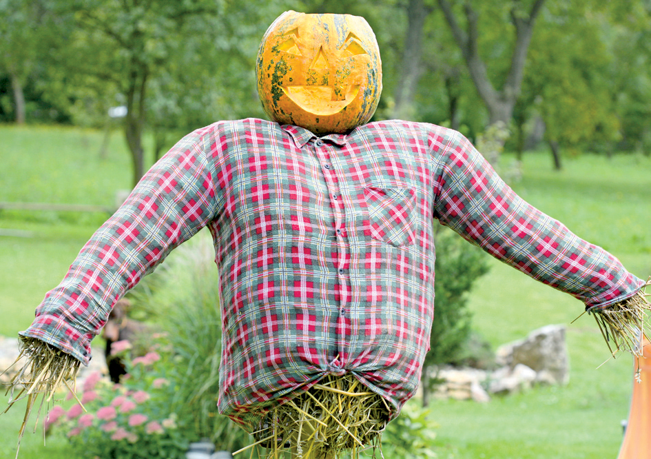Záhradný strašiak s košeľou vypchanou slamou a hlavou z tekvice