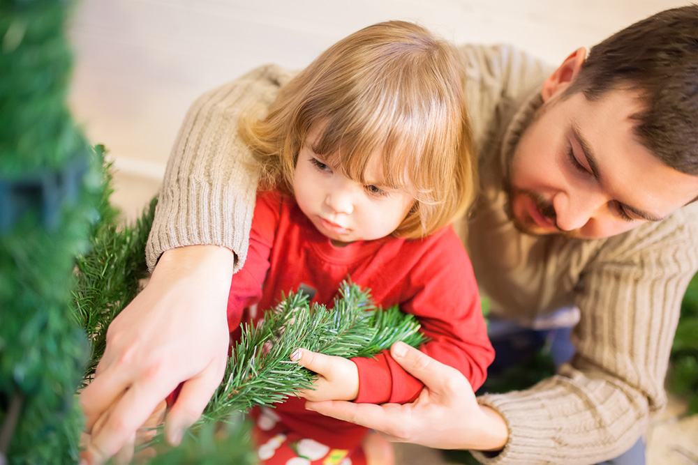 Otec s malou dcérou montujú umelý vianočný stromček
