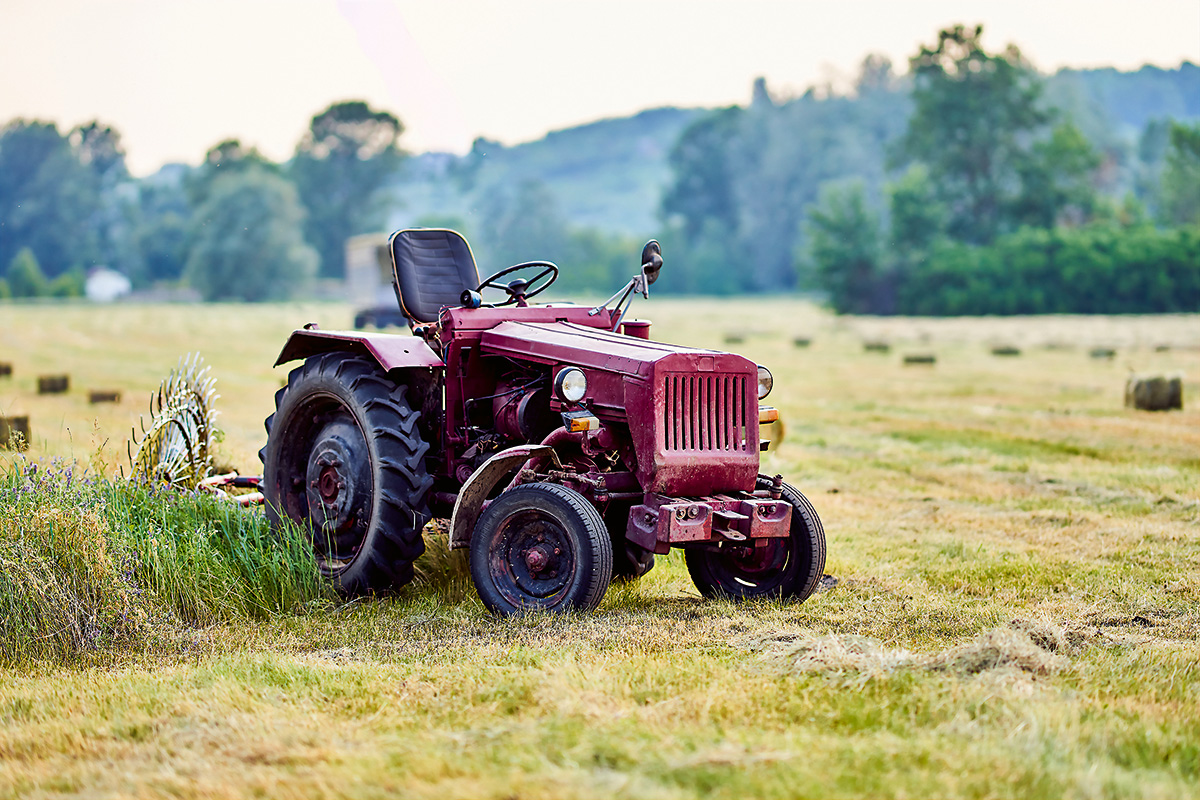 Kosenie trávy na lúke so starým červeným traktorom