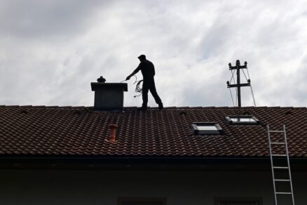 Kominár čistí komín na streche rodinného domu